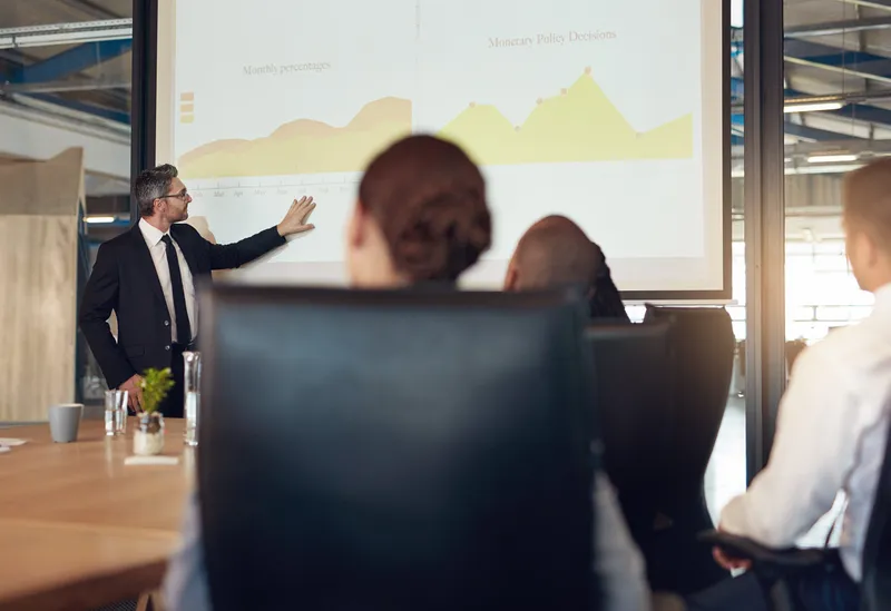 Man presenting metrics to a boardroom.