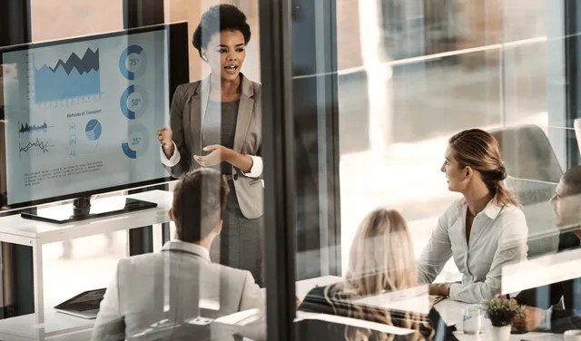 Three training professionals consider charts during a corporate meeting.