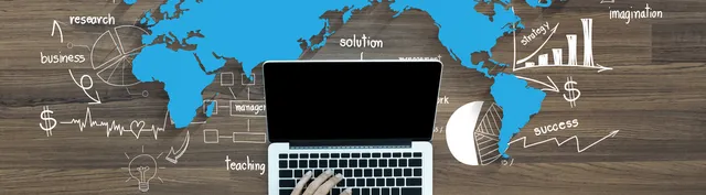 Laptop on a wooden desk with a world map and hand-drawn business strategy sketches including charts, dollar signs, and organizational diagrams.