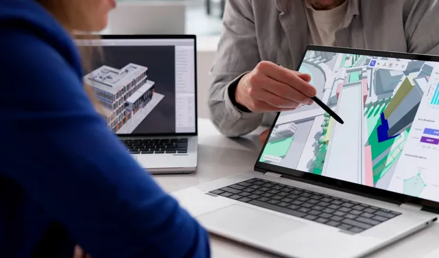 Man gesturing at a 3-D map on a laptop with his pen while explaining something to the learner seated in front of him.