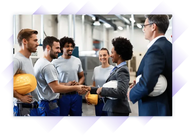 Female executive shaking hands with a factory worker in a group meeting with industrial staff.