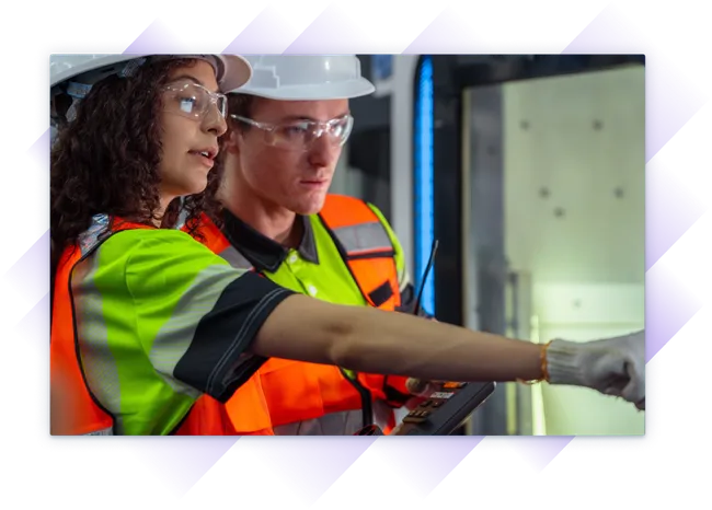 Two engineers in safety gear reviewing equipment controls and inspecting machinery.