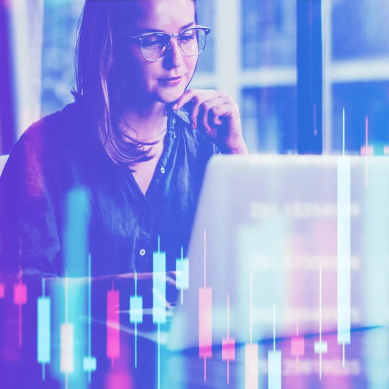 Woman with glasses working on a laptop overlaid with a translucent financial data visualization chart in blue and pink tones.