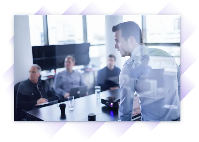 Business team in a boardroom meeting, attentively listening to a presenter with data projected on a screen.
