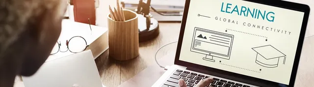 A person types on a laptop displaying the words Learning and Global Connectivity above icons of a screen and graduation cap, with pencils and a book on the wooden desk.