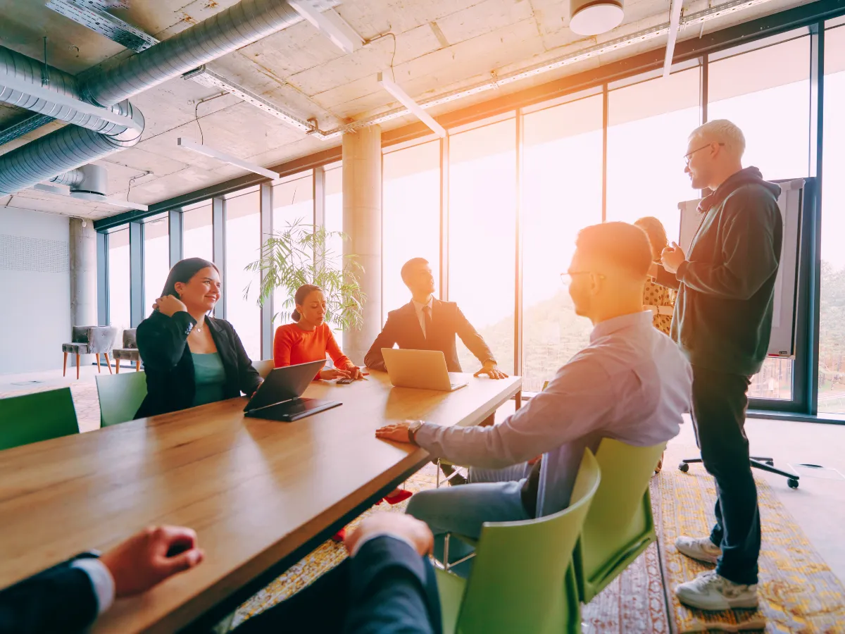 Training teams discusses automated communications in an open boardroom.