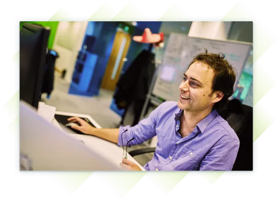 A team member smiling as he works at his computer.