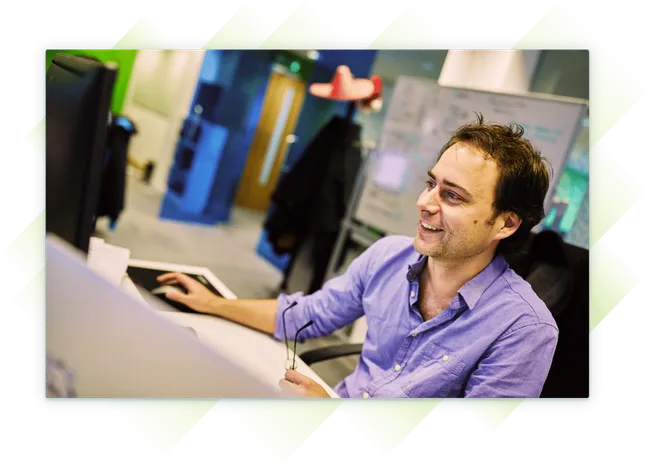 A team member smiling as he works at his computer.