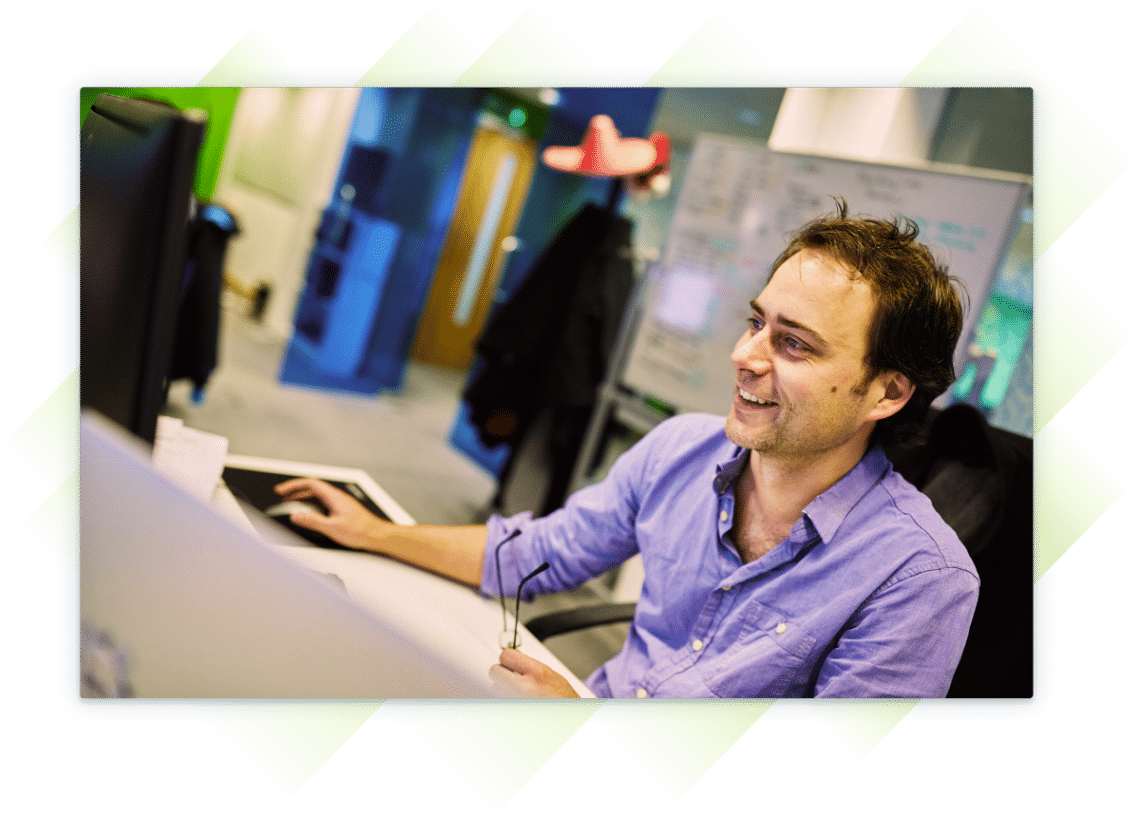 A team member smiling as he works at his computer.