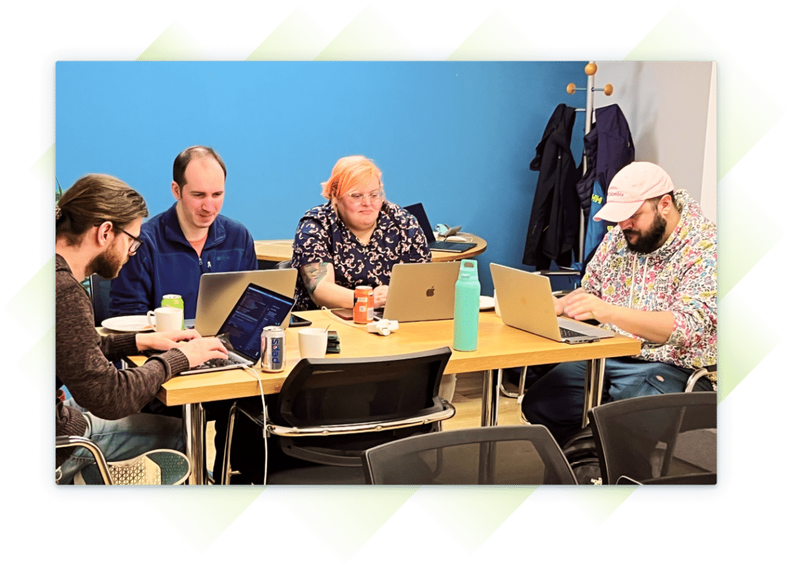 Group of coworkers at a table collaborating while working on laptops.