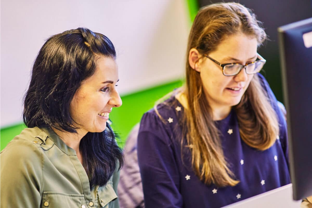 Two women talking at a computer.