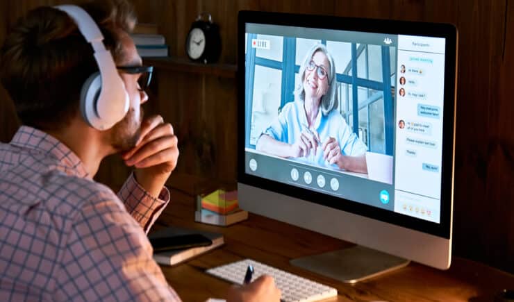 Male student wearing headphones taking online course training, watching webinar, remote seminar university class, virtual learning with social distance web teacher, tutor or coach on computer screen.