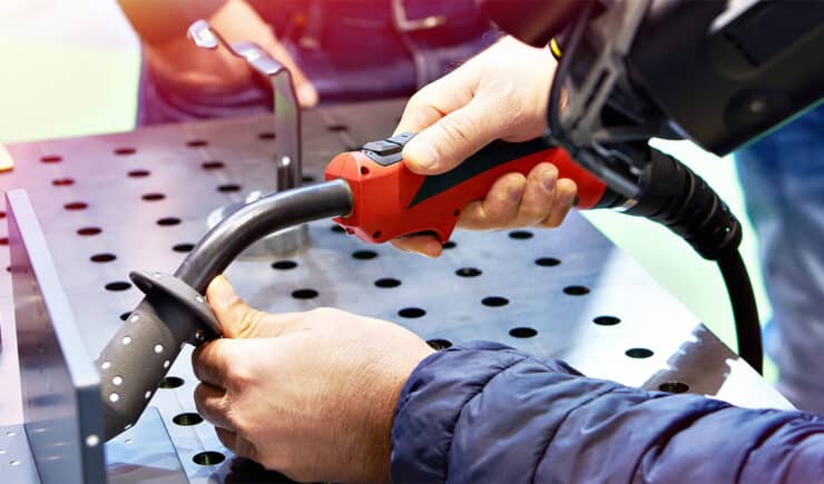 A hands-on customer training session in progress, where an instructor guides a trainee in using specialized welding equipment.