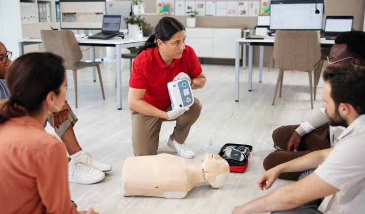 Learners attend a safety course with an instructor giving a lesson on how to use medical equipment on a dummy.