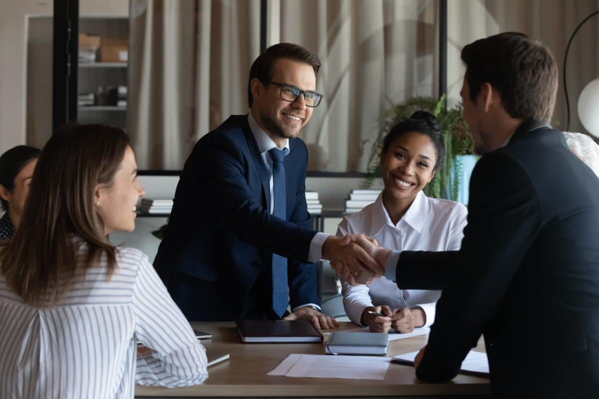 Image of training sales pros shaking hands and closing a deal.