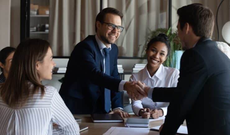 Image of training sales pros shaking hands and closing a deal.